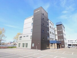 A multi-story hotel with a modern design, featuring a parking lot in front.