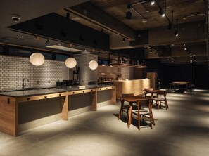 A modern kitchen with a brick backsplash, wooden counter, and bar stools. - Hotel Mates Asahikawa (Asahikawa)