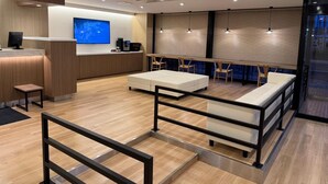 Un hall d’hôtel moderne avec un comptoir d’accueil, un espace salon et un grand écran de télévision.