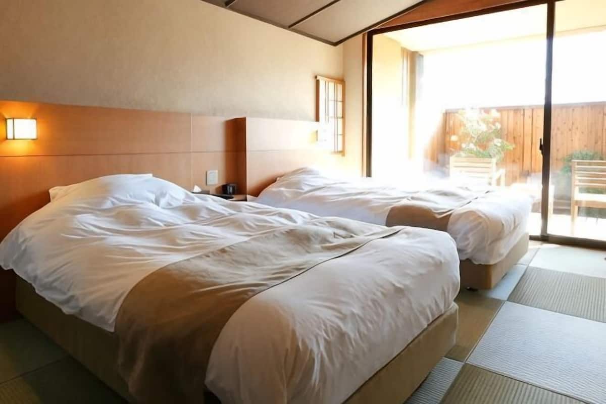 A hotel room with two beds, a sliding glass door to the outside, and a wooden headboard.