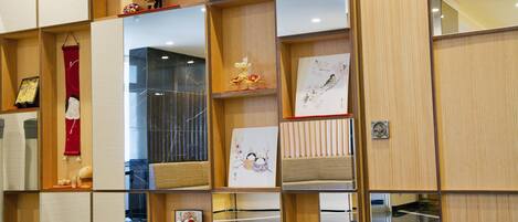 A modern hotel room with a wooden wall unit displaying various decorative items.