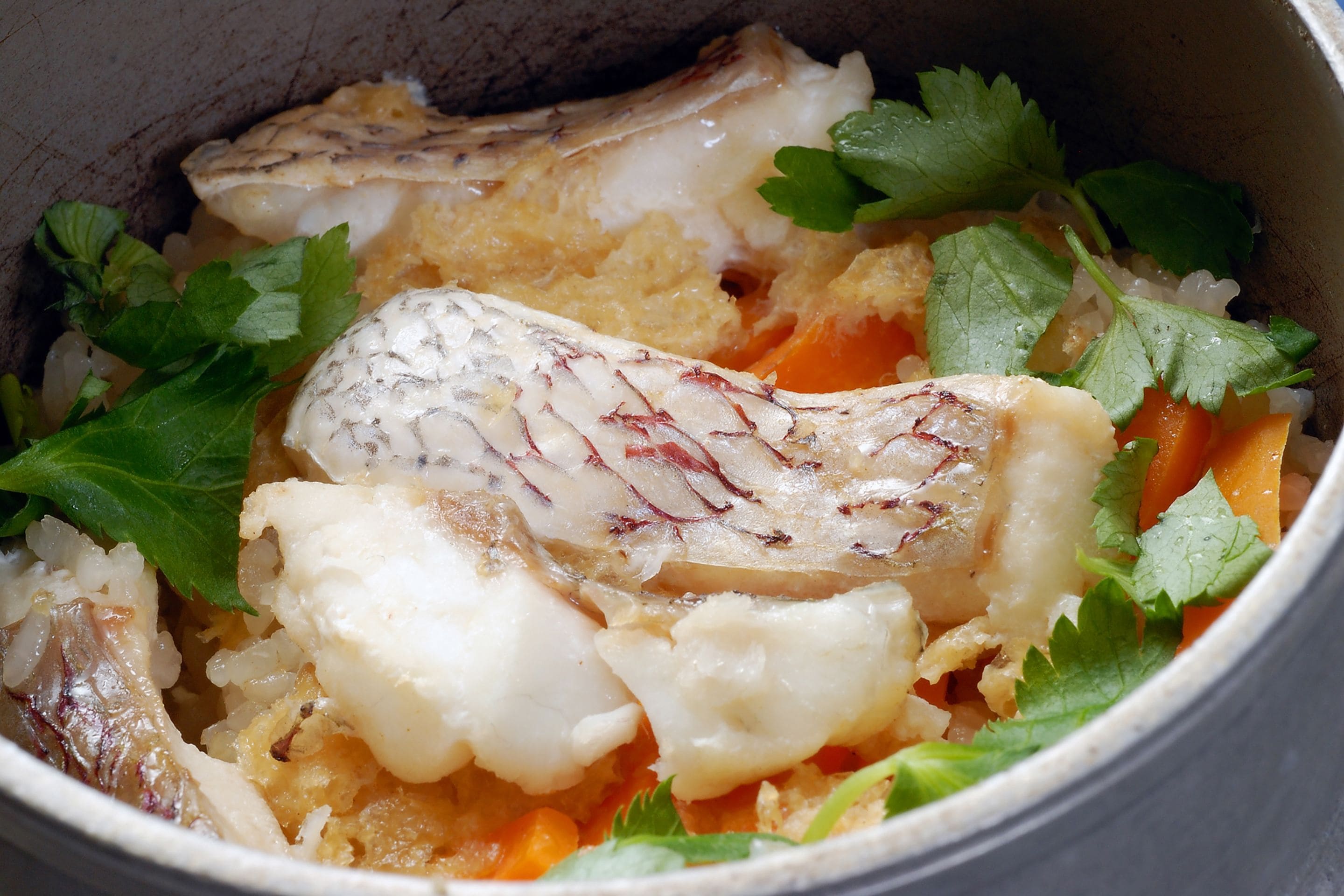 Un tazón de pescado con arroz y verduras.