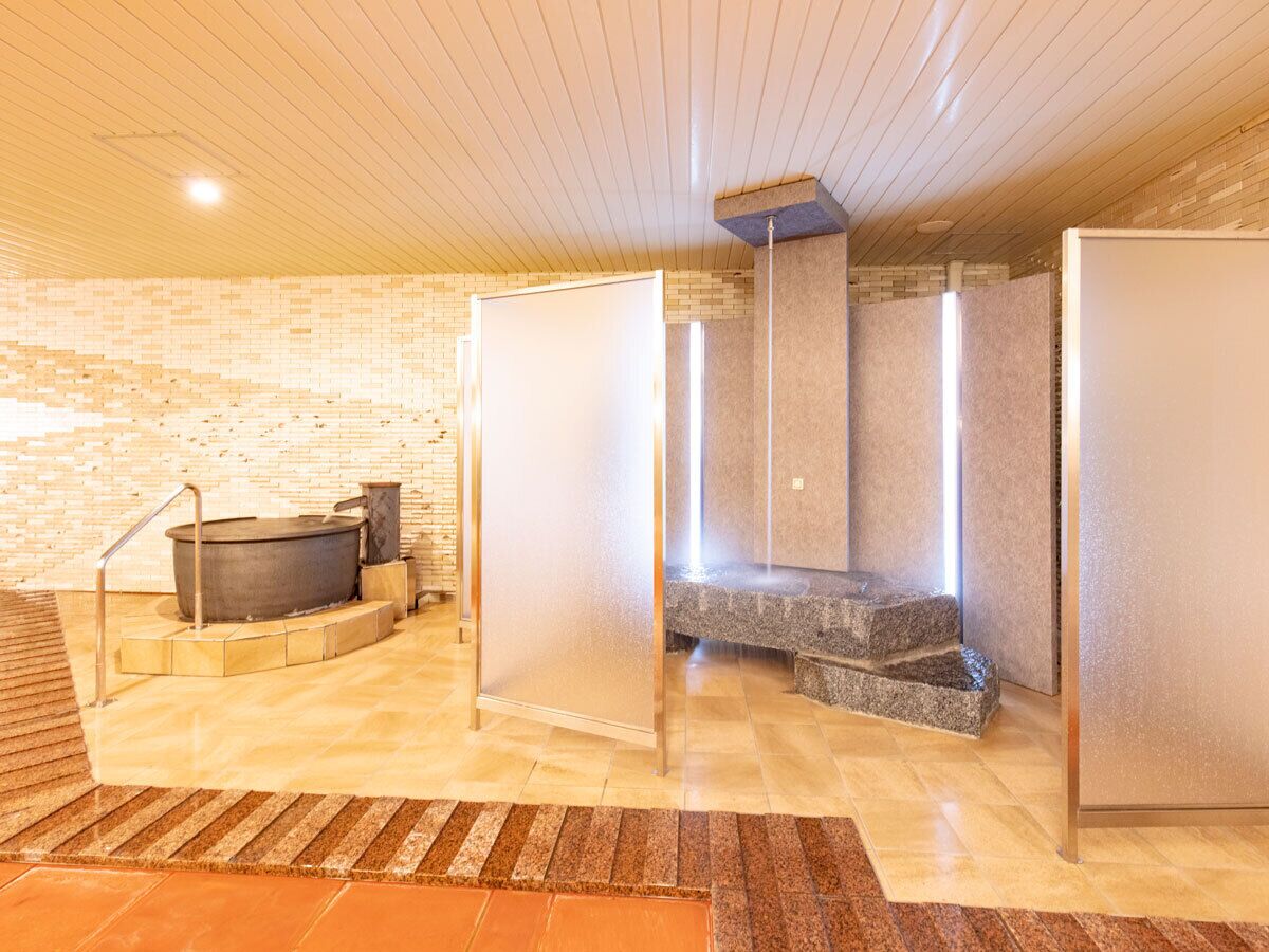 A spa area with a hot tub, a stone bench, and a sauna.