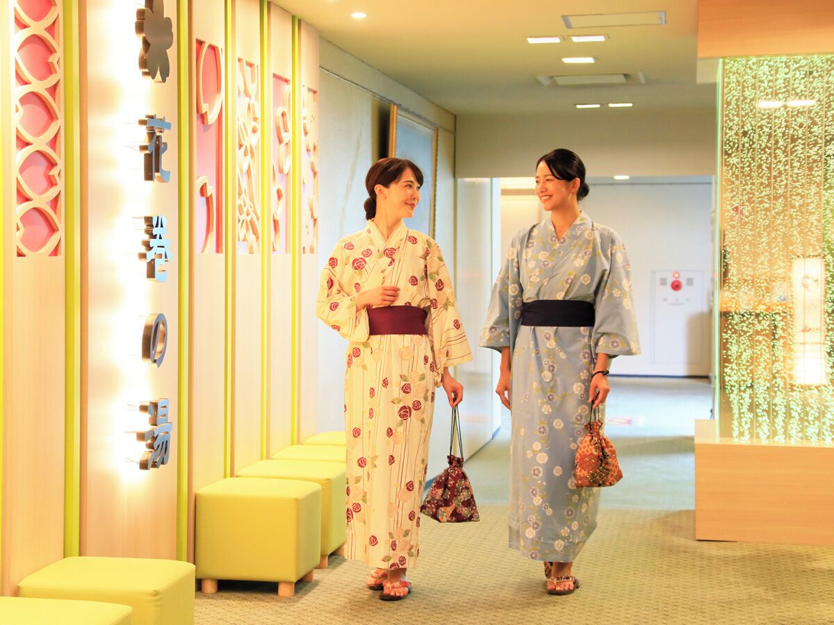 Two individuals in traditional attire walking in a hallway with modern decor and seating areas.