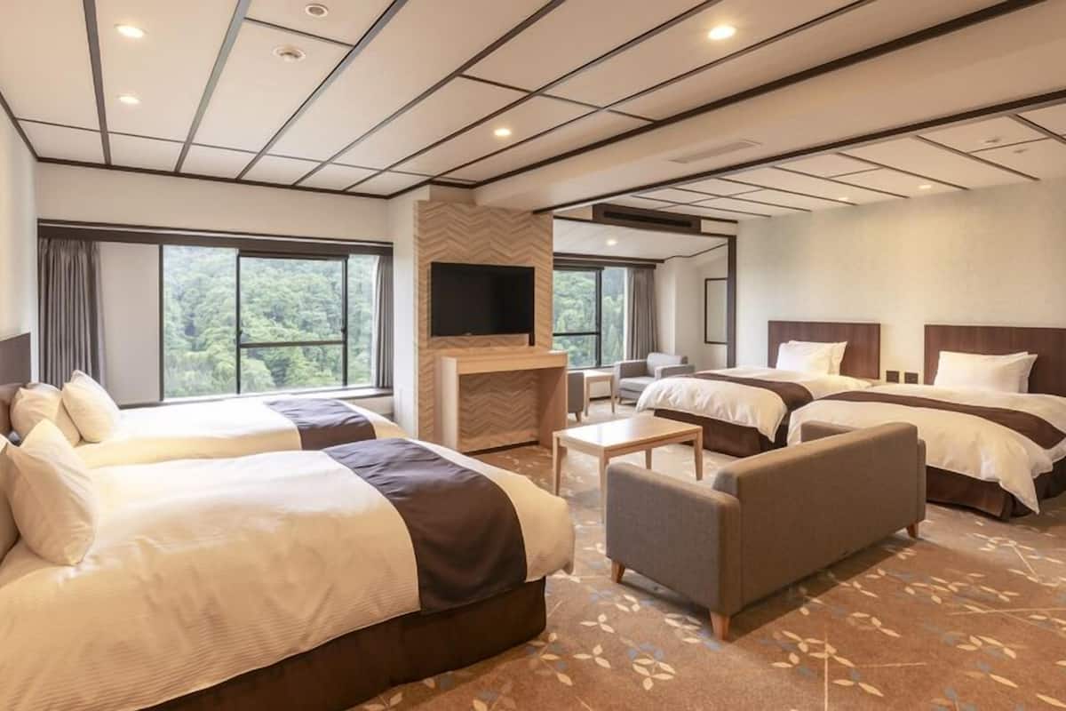 Ett hotellrum med två sängar, en soffa, en TV och en öppen spis.