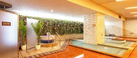 A modern indoor pool area with a wooden ceiling, a brick wall, and a tiled floor.