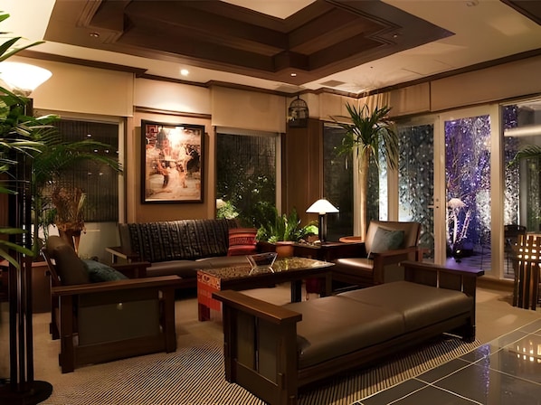 A modern living room with a sofa, armchairs, a coffee table, and a large window with a view of a garden.
