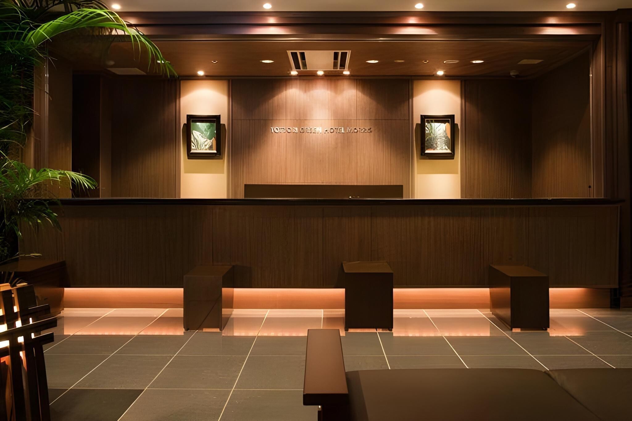 A reception area with a wooden reception desk, two framed pictures, and a bench.