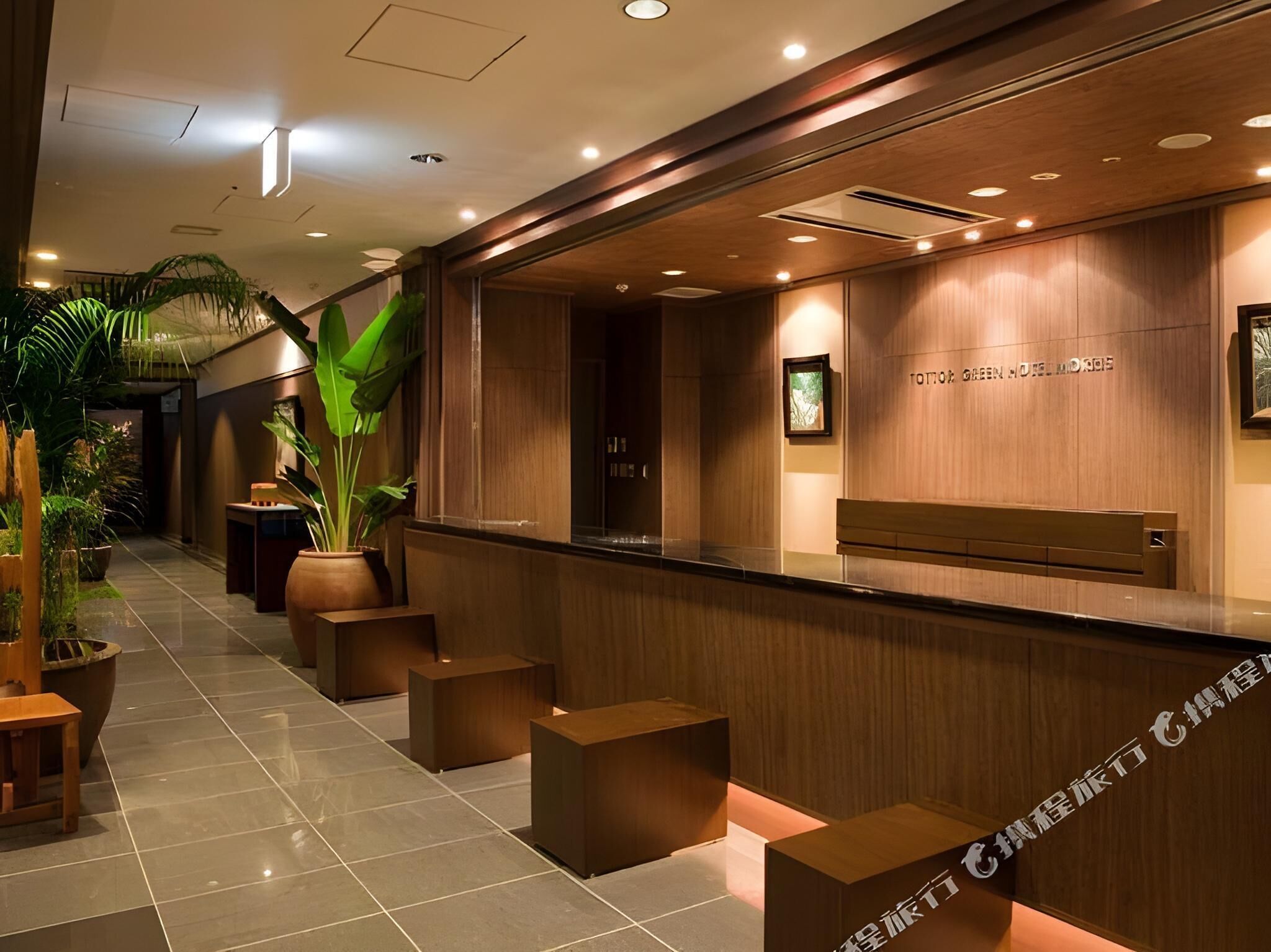A reception area with a wooden reception desk, potted plants, and a tiled floor.
