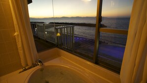 Un baño con bañera, ventana con vistas al mar y balcón con barandilla.
