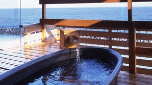 Un jacuzzi en una terraza de madera con vistas al océano.