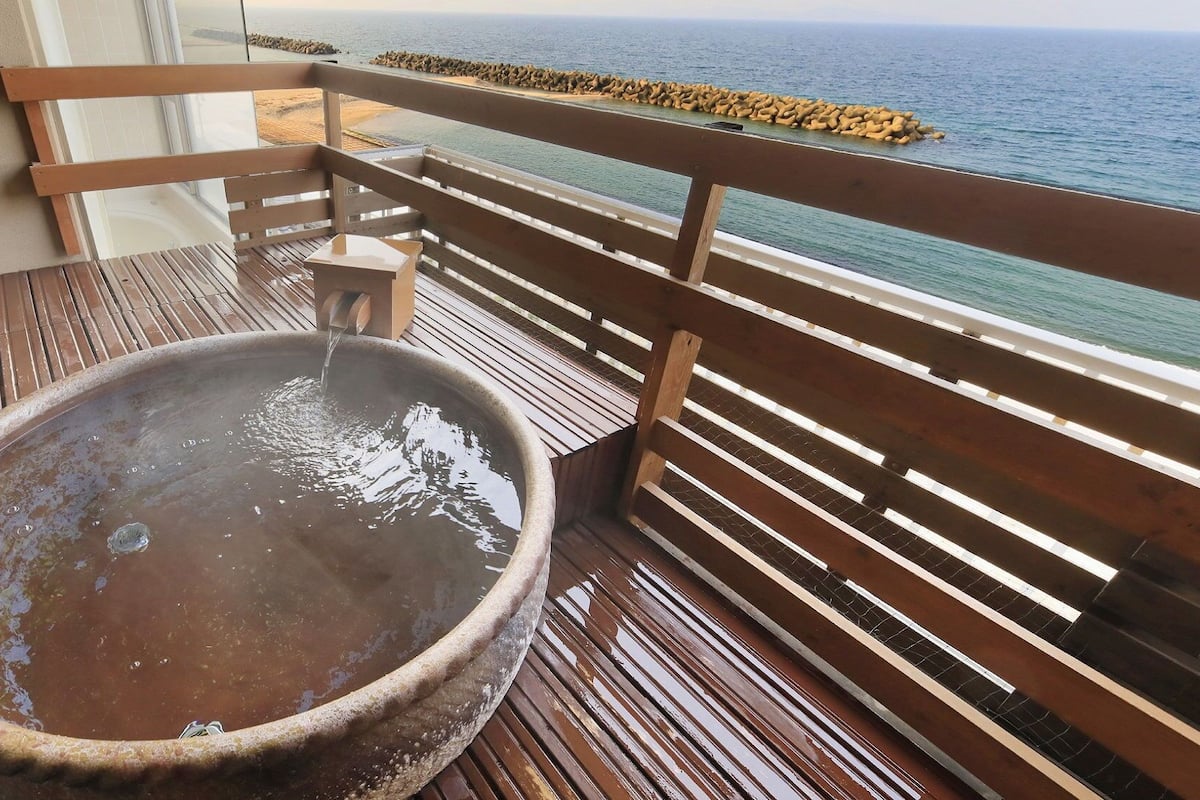 Une terrasse en bois avec un jacuzzi et vue sur l’océan.