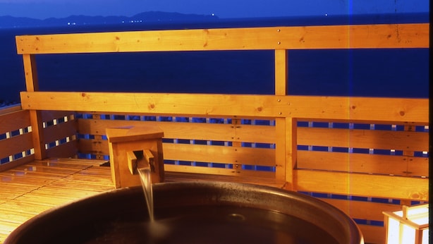 Una terraza de madera con un jacuzzi grande, una mesita y un farol.