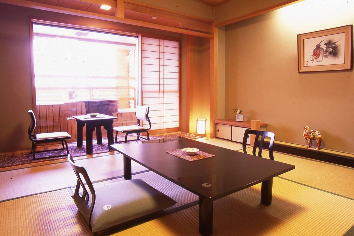 A traditional Japanese room with tatami flooring, a low table with cushions, and sliding doors.