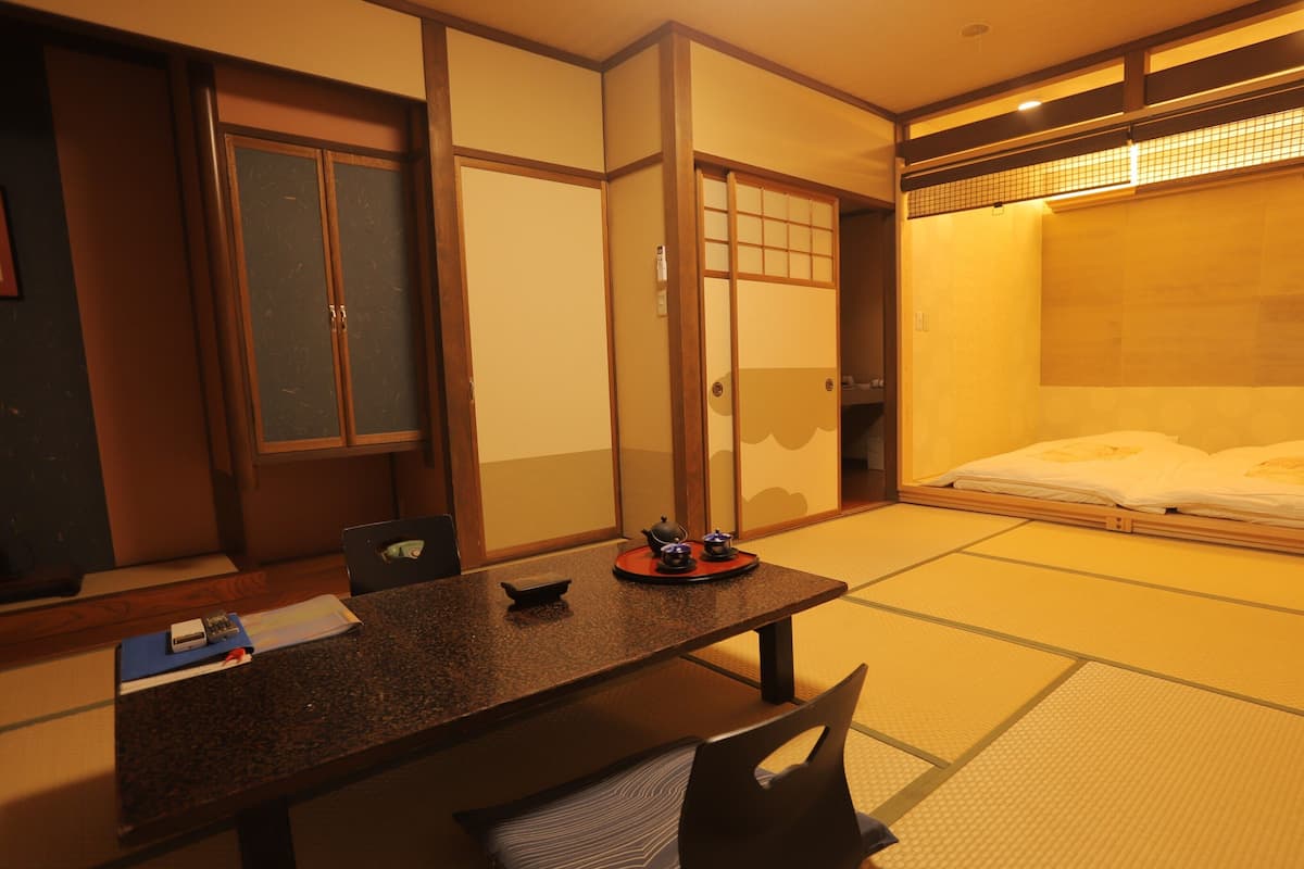 Una habitación japonesa tradicional con suelo de tatami, una mesa baja con un juego de té y un futón.