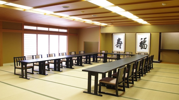 A conference room with a long table and chairs, large windows, and traditional Japanese calligraphy on the walls.