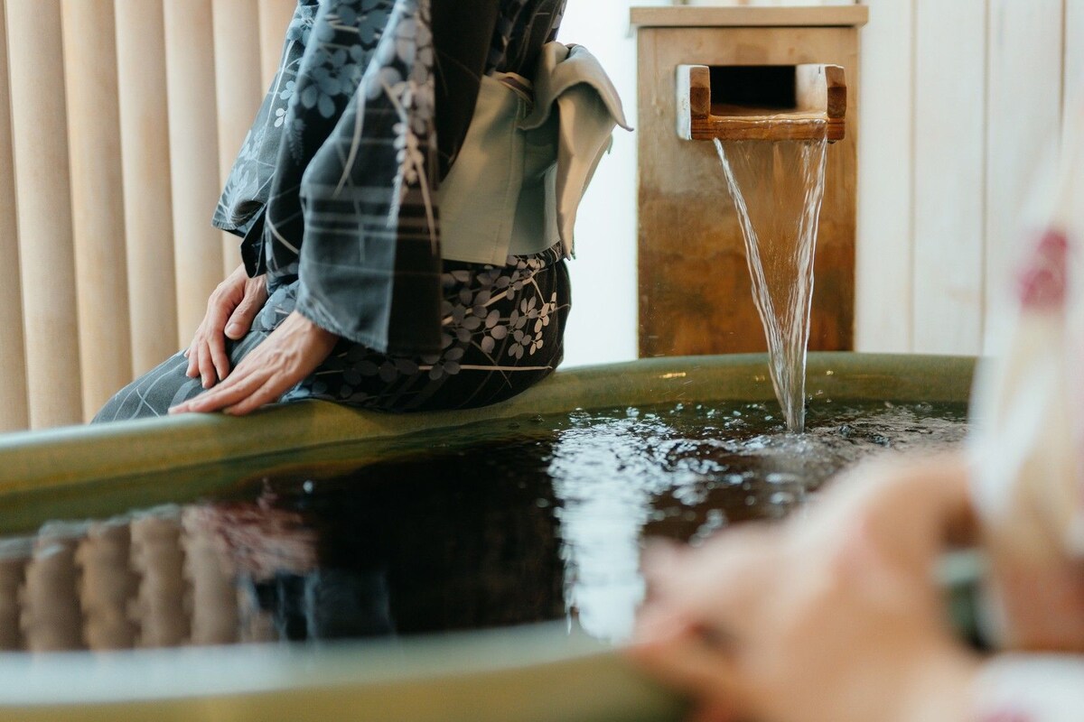 A person sitting by a water feature with a wooden structure.