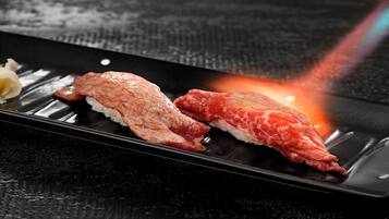Two pieces of sushi on a black plate with a light source in the background.