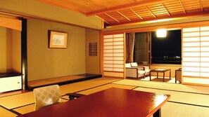 Une pièce de style japonais traditionnel, avec un sol recouvert de tatamis, une table basse, un canapé et des portes coulissantes.
