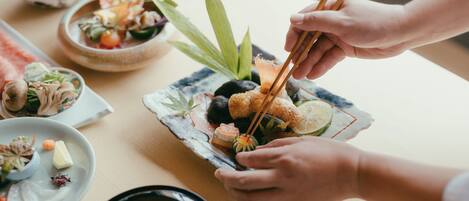 Una mesa de comedor con diversos platos, como sushi, verduras y un tazón de sopa.
