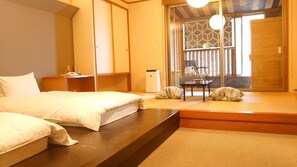 A traditional Japanese-style room with tatami flooring, a low table, and a sliding door leading to a balcony. - Katayamazu Onsen Tokigasane (Kaga)