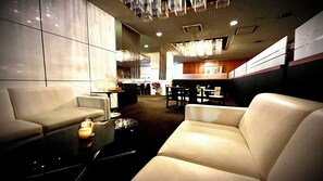 A modern interior with seating areas, a kitchen in the background, and a decorative ceiling. - Katayamazu Onsen Tokigasane (Kaga)