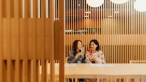 Dos personas sentadas en una mesa, con un panel de madera en el fondo.