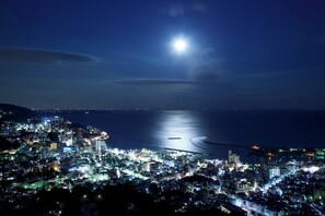 A nighttime cityscape with a prominent view of the sea and a bridge.