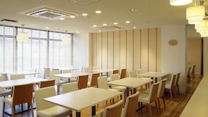 A modern dining area with white tables and chairs, wooden flooring, and recessed ceiling lighting. - Hotel Green Palace (Sendai)