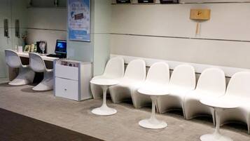 A reception area with white chairs, a reception desk, and a clock on the wall.