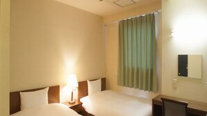 A hotel room with two beds, a desk, a chair, a lamp, and a window with curtains. - Hotel Green Palace (Sendai)