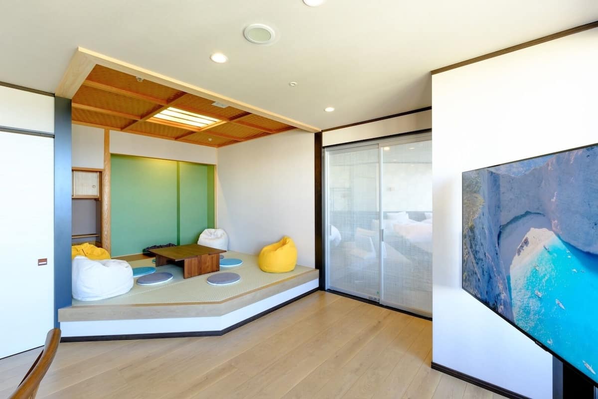 A modern hotel room with a large window, a wooden ceiling, and a flat-screen TV.