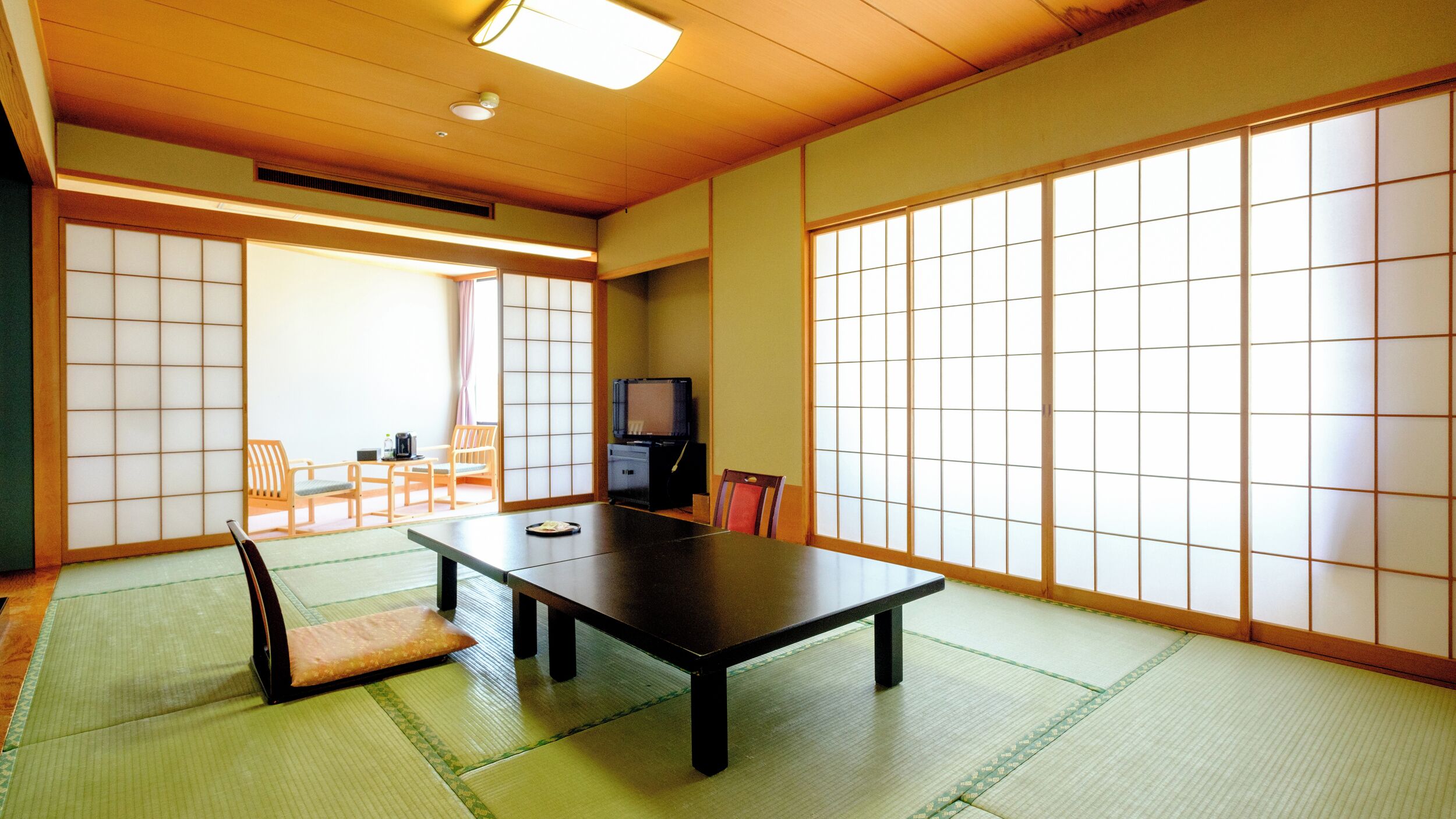A traditional Japanese room with tatami flooring, a low table, and sliding doors.