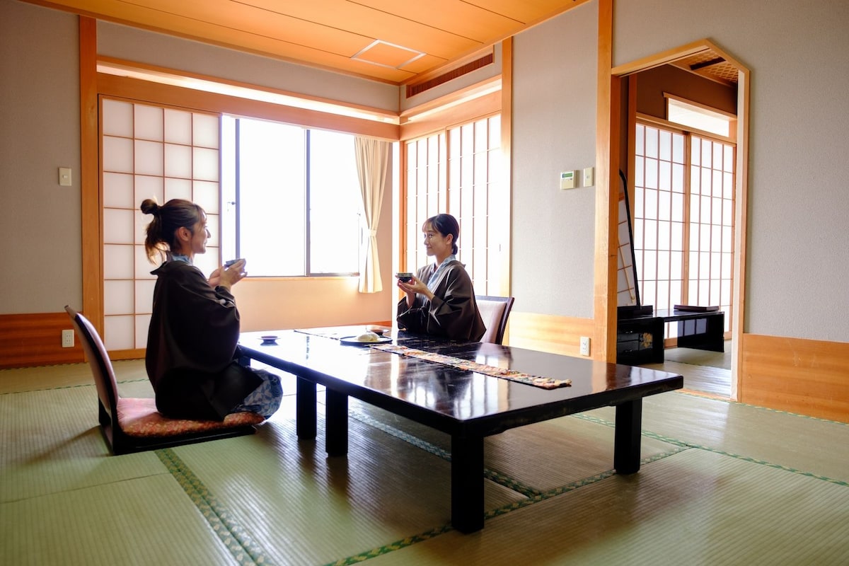Une pièce de style japonais traditionnel, avec un sol recouvert de tatamis, une table basse et des portes coulissantes.