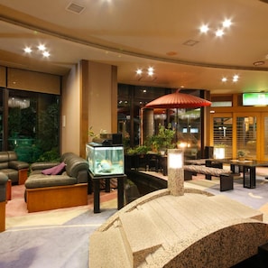 A modern interior with a seating area, a fish tank, and a decorative stone structure. - Kaike Onsen Fuyo Annex (Yonago)