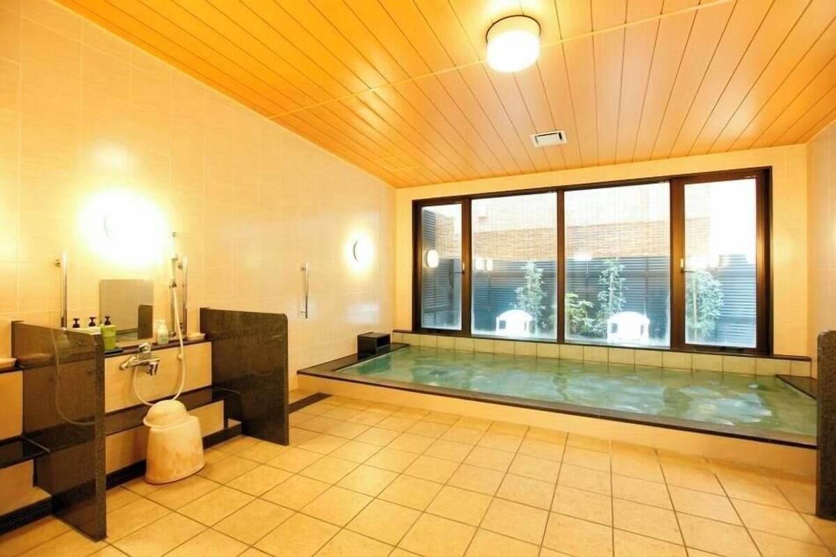 Un bagno moderno con vasca idromassaggio vetrata, soffitto in legno e ampie finestre.