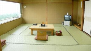 A traditional Japanese room with tatami flooring, a low table with cushions, a television, and a cabinet. - Hanayubi Nihonkai (Tsuruoka)