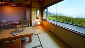 A traditional Japanese room with tatami flooring, a low table, and a view of a lush green landscape through large windows. - Hanayubi Nihonkai (Tsuruoka)