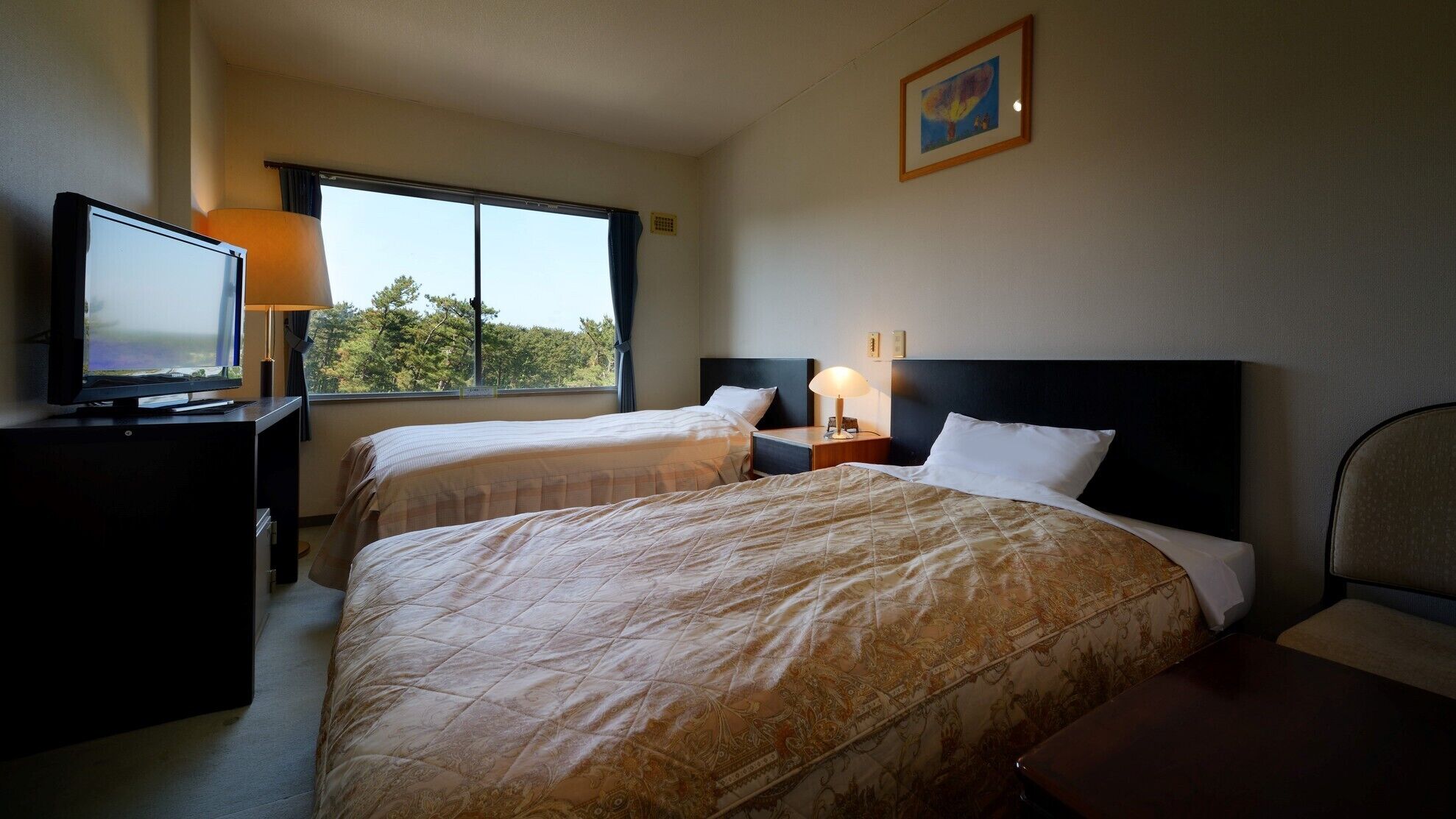 A hotel room with two beds, a TV, a window with a view, and a painting on the wall.