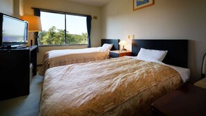 A hotel room with two beds, a TV, a desk, and a window with a view of trees. - Hanayubi Nihonkai (Tsuruoka)