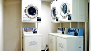 Two front-loading washing machines with control panels, placed in a laundry room with a white interior. - Matsue Plaza Hotel Honkan (Matsue)