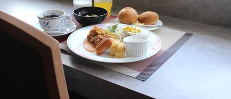Una mesa de desayuno con un plato de comida, dos vasos de jugo de naranja, un tazón de sopa y una taza de café.
