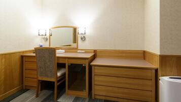 Ein Hotelzimmer mit Holztisch, einem Stuhl, einem Spiegel und einer integrierten Waschmaschine.