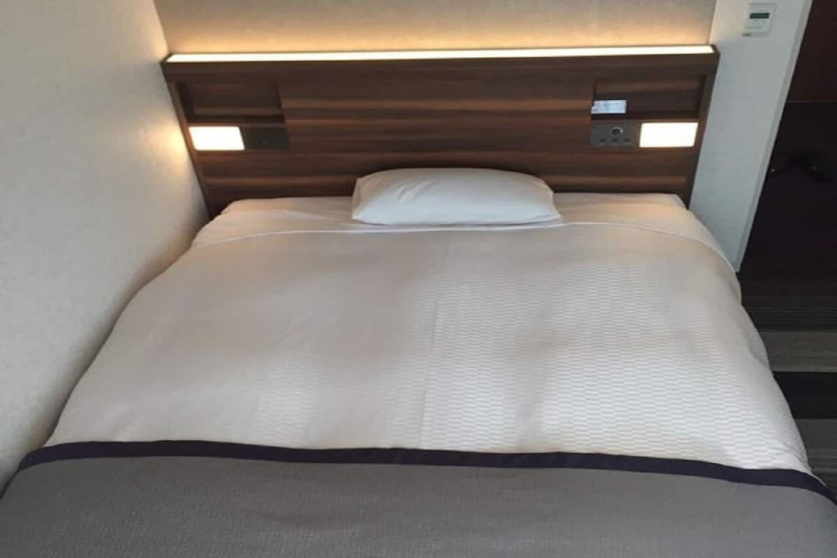 Un letto singolo con testiera, cuscino e coperta.