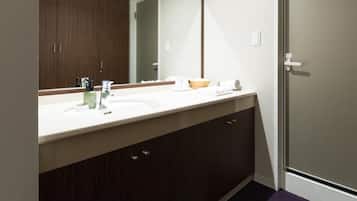 A bathroom with a double sink, a large mirror, wooden cabinets, and a door.