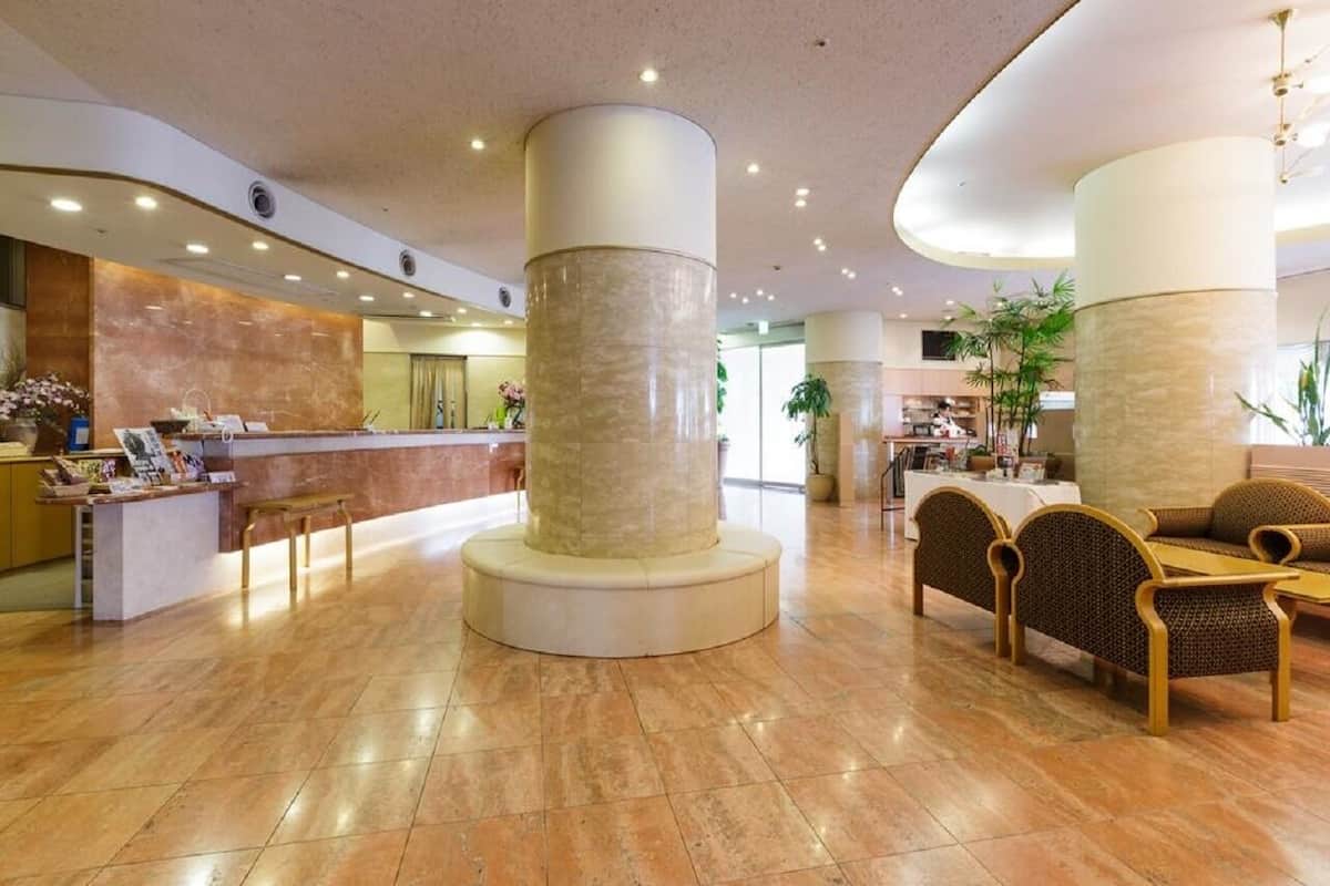 Hall d'albergo con reception, area salotto e ampie colonne.