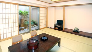 A traditional Japanese room with tatami flooring, a low table with a bowl, a television, and a small decorative item. - Kochi Pacific Hotel (Kochi)