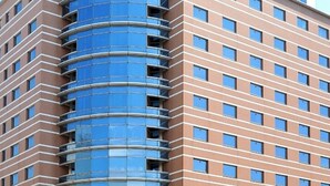 A multi-story hotel with a distinctive curved glass facade and a flat roof. - Kochi Pacific Hotel (Kochi)