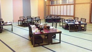 Ein traditioneller japanischer Raum mit Tatami-Boden, Holztischen und Shoji-Schirmen.