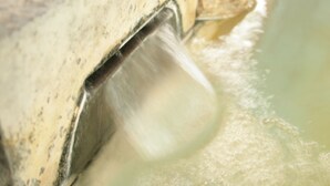 Eine Nahaufnahme eines Wasserausstoßers mit metallischer Struktur, wahrscheinlich Teil einer Springbrunnenanlage oder eines Wasserspiels.